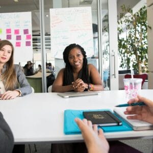 Professional team meeting with diverse group in a modern office setting, discussing project details.